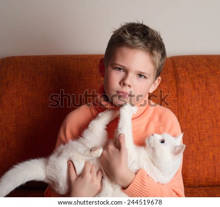Child hugging a white cat. Friends Ã¢Â?Â? a boy and a cat. Boy with a pet on his hands.