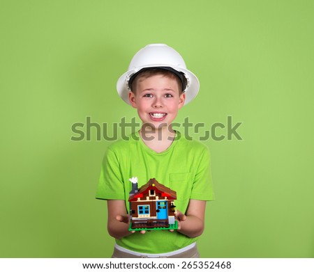 House model in child hands. Family house concept - portrait of cute boy with a house on green background. Concept of real estate and engineering.