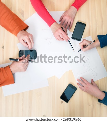 Close-up top view of businesspeople hands holding pens, papers and smartphones on the table. Teamwork concept.
