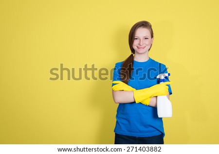 Spring cleaning. Cleaning woman with cleaning spray bottle happy and smiling. Beautiful cleaning girl isolated on yellow background with copyspace.
