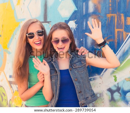 Two funny affectionate teenagers friends laughing and having fun outdoors. Bright stylish lifestyle urban portrait.