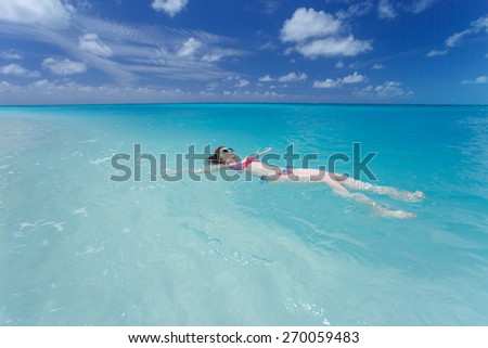 Woman floating and relaxing in turquoise waters at colorful tropical beach