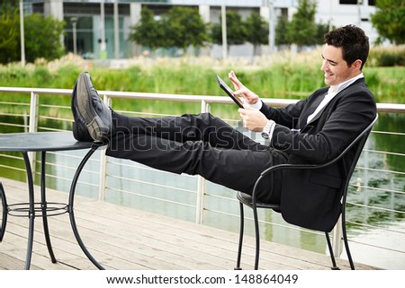 Young successful businessman relaxed outdoors with tablet