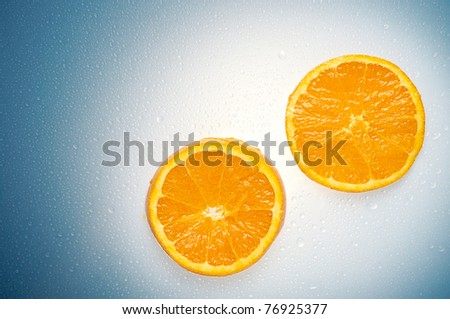 Two oranges over a white and blue wet background with water drops