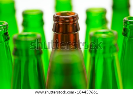 Nine green and one brown bottles. Central brown bottle neck in focus.