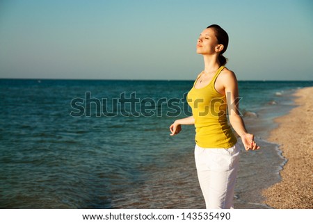 Woman doing yoga on the beach in the morning sunrise.