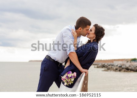 Gentle bride and handsome groom kissing on the pier. Happy newlyweds on the beach.