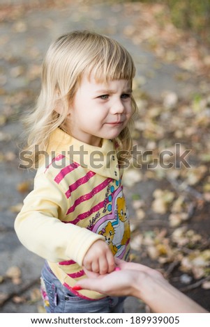 Little girl with a sour face taking candy from my mother\'s hands.