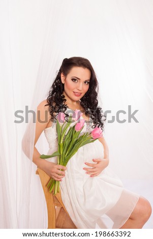 Beautiful pregnant woman with tulips. Happy pregnancy.