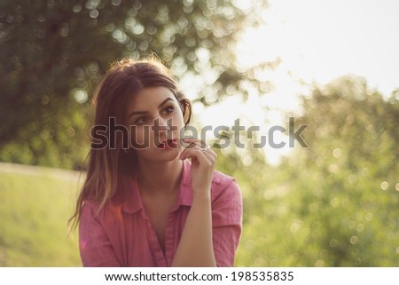 Beautiful and attractive woman landscape portrait watching at something, wearing a pink shirt and multiple gold rings