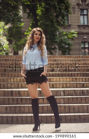 Beautiful Woman posing on stairs wearing sexy shorts black with lace and over knee boots
