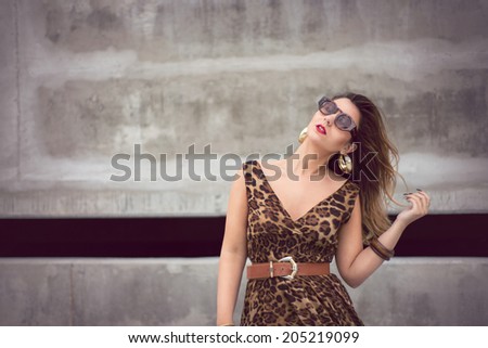 Beautiful woman in animal print dress in urban concrete jungle background