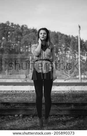 Black and white fashion shoot of gorgeous girl posing straight in full lenght outdoor wearing a leather skirt and a shirt with stripes