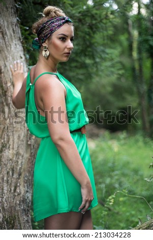 Beautiful side profile portrait of a woman wearing a sexy green dress and scarf, posing in the forest. Nature Eco Friendly