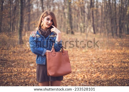 Beautiful woman portrait in a romantic autumn fall scenery wearing a denim jacket with geometric print. Fashion female ready for shopping