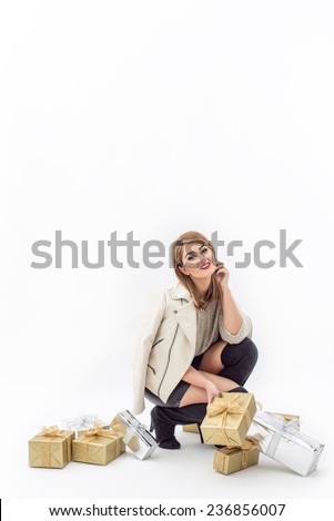 Fashion Woman posing with beautiful gifts in gold and silver packaging for Christmas holiday, isolated on white background. Glittered Ribbons and sweater for new years eve