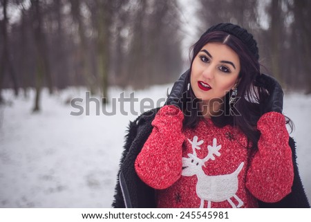 Cute girl wearing fashion deer sweater and sexy leather pants in winter snow scenery