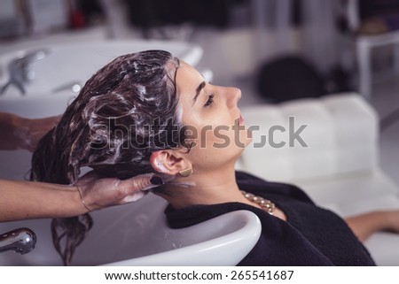 Hair stylist washing model\'s hair. Shampoo treatment
