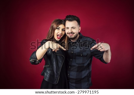 Happy couple isolated on red, pointing down