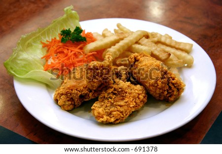 Deep fried chicken pieces with southern spices, fries, shredded carrots and a leaf of lettuce.