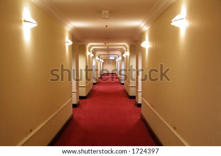 Long hotel corridor with red carpet and yellow wallpaper