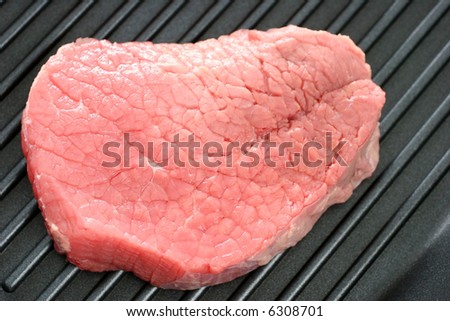 A raw round eye steak on a grilling pan