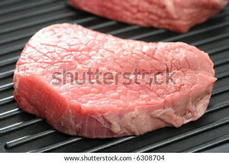 A raw round eye steak on a grilling pan