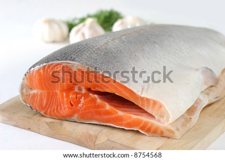 Large slab of tail portion of fresh Atlantic salmon on wooden chopping board