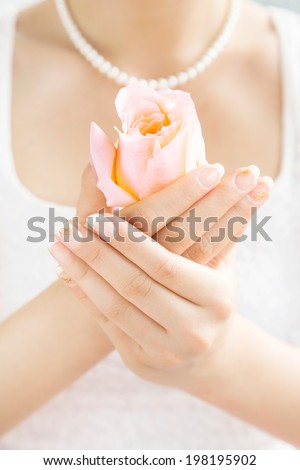 Bride holding a rose flower in her hands. Beautiful nail art on her nails.Wedding.