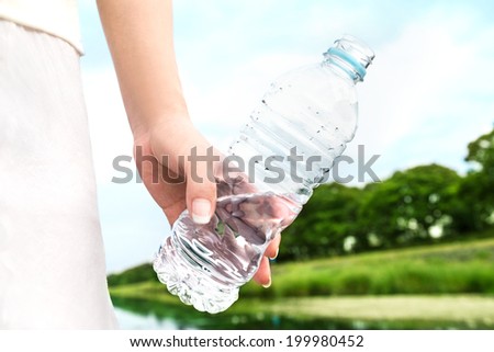 A woman carrying the bottle of the water in the park. Water from nature. Don't dump plastic.