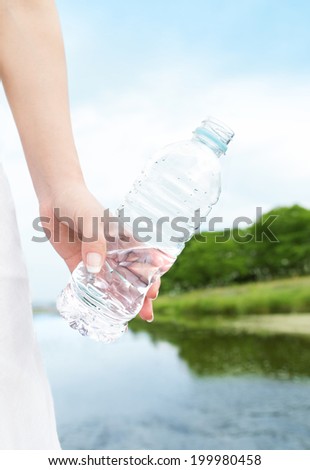 A woman carrying the bottle of the water in the beautiful nature. Fresh water from nature.Environmental issue.