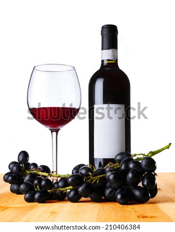 Red wine in the glass and the bottle with fresh grape on the wood table. Isolated on white.