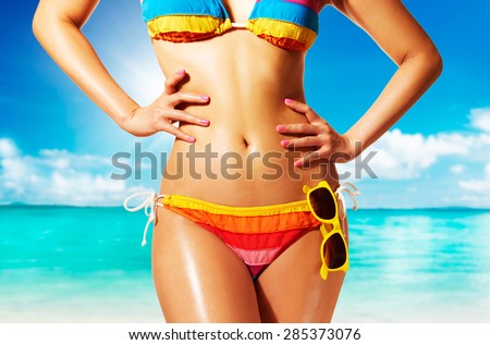 Colorful bikini woman with tanned skin. Summer fashion on the beach.