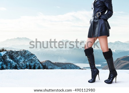 Beautiful legs woman with black leather coat jacket,high heels boots standing in the winter mountain. Italy Swiss Alps mountain.