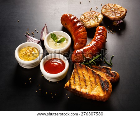 Grilled sausage with different kinds of dips  on a blackboard background