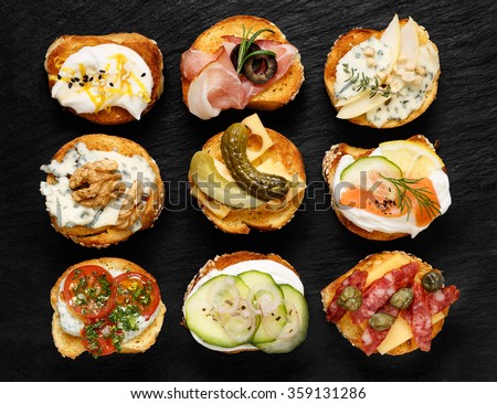 Crostini with different toppings on black background. Delicious appetizers