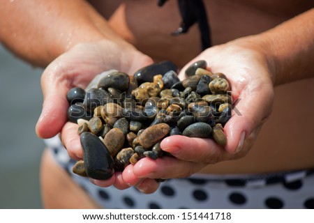 Woman keeping colored pebbles in hand on the beach in Anapa.