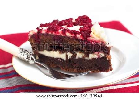 Raspberry chocolate layered cake with white butter cream, jam and berries on white background.