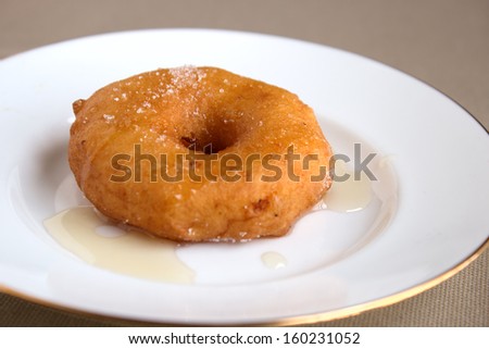 French traditional beignet with apple sugared on white plate with honey.