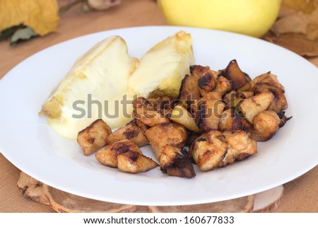 Chopped chicken meat cooked with quince served on white plate with potato and melted cheese.