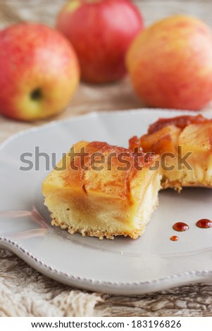 Traditional Russian charlotte apple cake with caramel on golden napkin and apples on the background.