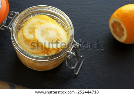 Sliced lemons and mixed with sugar in transparent jar; preparation for winter time to prevent cold, black background.