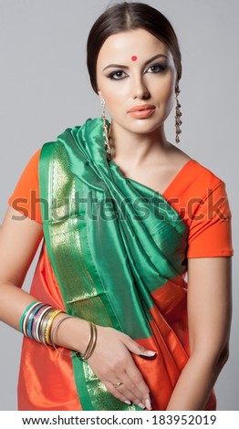 Beautiful young indian woman in traditional clothing with make-up and jewelry. Close-up portrait of a brunette traditionally dressed in sari. Bollywood dancer girl from India. Arabian bellydancer