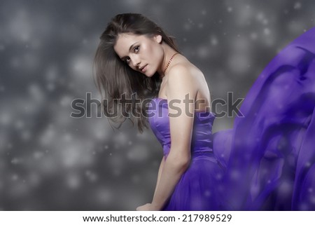 Winter Beauty Woman. Christmas Girl Makeup and Blue Dress. Holiday Make-up. Snow Queen over Gray Snow Background.