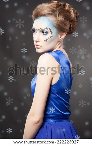 Winter Beauty Woman. Christmas Girl Makeup and Blue Dress. Holiday Make-up. Snow Queen over Gray Snow Background.