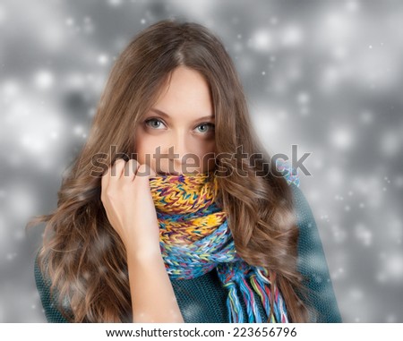 Beautiful woman with long hair wearing a sweater, scarf, hat and gloves.