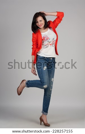Portrait of a young woman in jeans, high heels and red jacket. Fashion shot. Modern look and style. Short hairstyle.