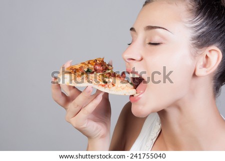 Beautiful close-up portrait of young woman eating pizza. Healthy and junk food concept. Skin care and beauty. Diet.