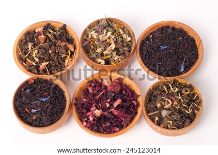 Dry tea in wooden plates, on white background. Leaves of red, green and black tea. Macro photo.