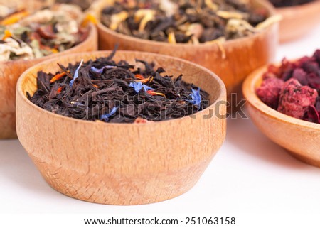 Dry tea in wooden plates, on white background. Leaves of red, green and black tea. Macro photo.